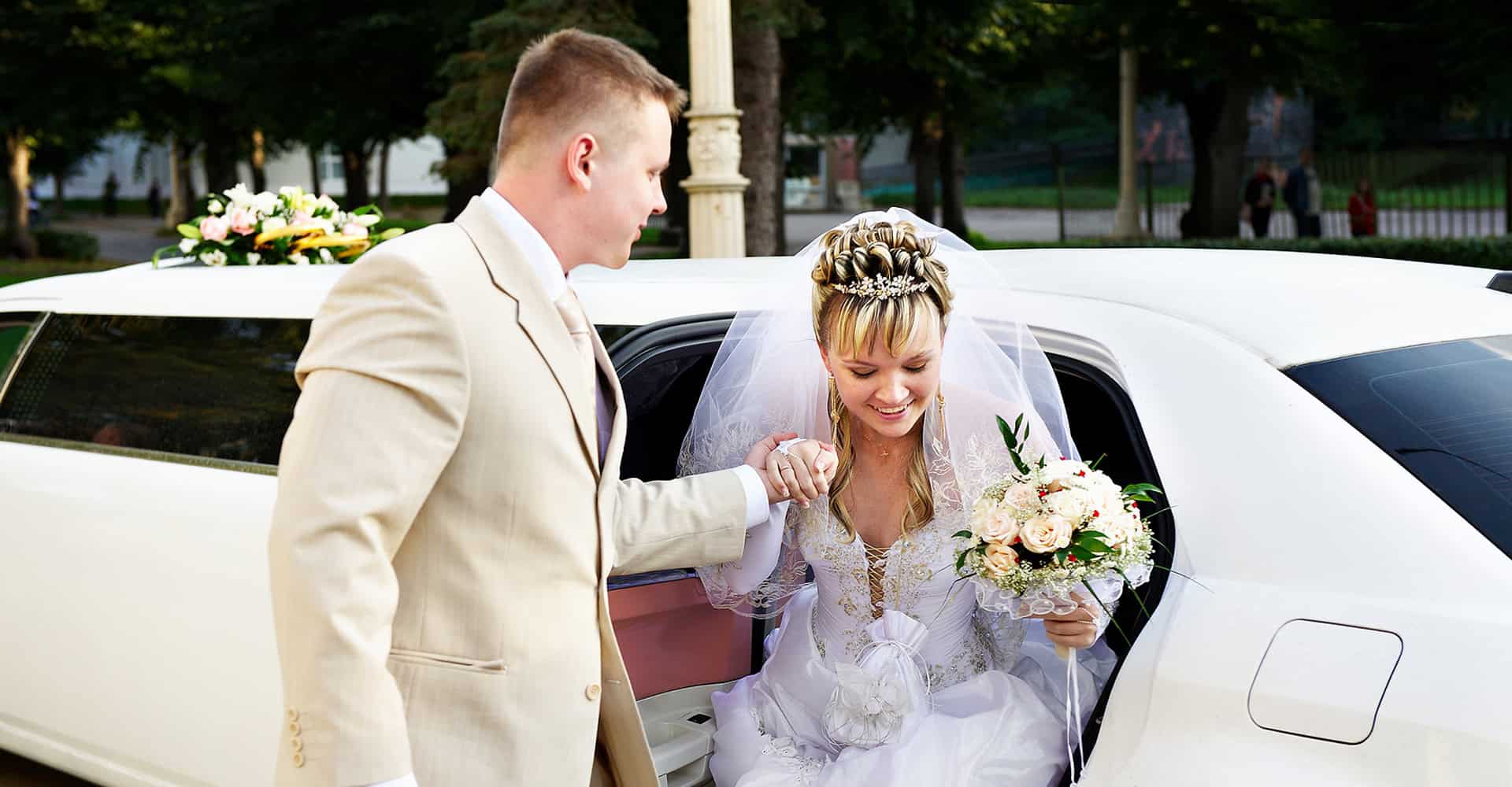 Elegant white stretch limousine arriving at Atlanta wedding venue for bride and groom